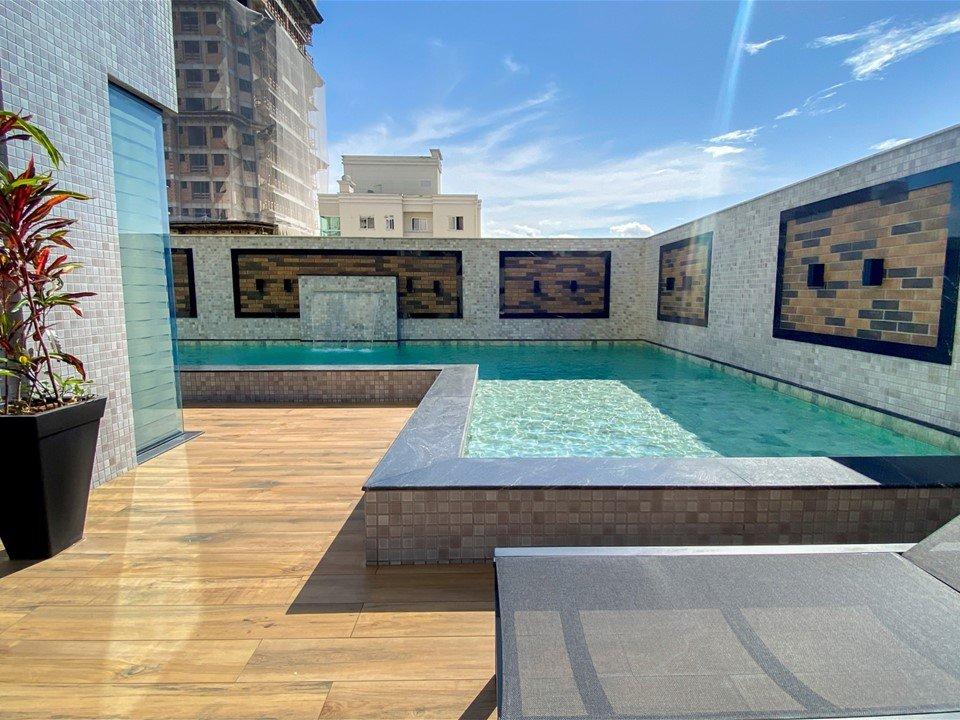 Piscina do Long Beach Residence, com deck de madeira e parede revestida em mosaico