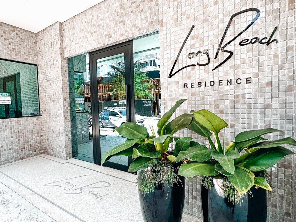 Porta de entrada do Long Beach Residence, com letreiro e vasos de plantas